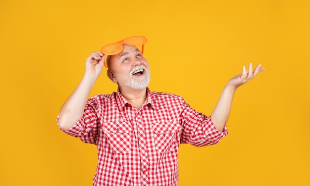 Surpris vieil homme âgé en chemise à carreaux et lunettes de fête sur fond jaune