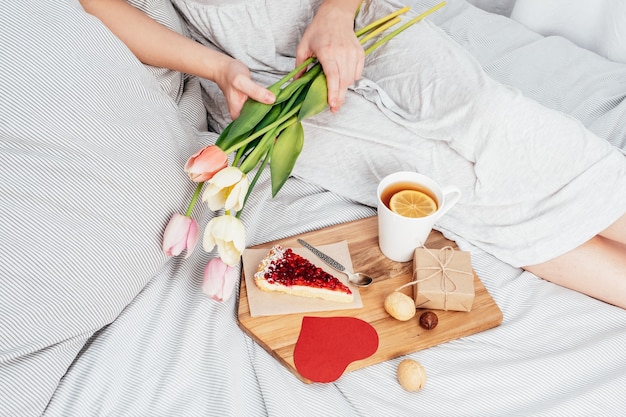 Surprise au lit. Petit-déjeuner, fleurs et cadeau pour une fille le jour de la Saint-Valentin. félicitations pour le 14 février.