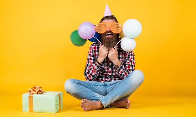 Surprise heureux homme tenant des ballons d'hélium colorés hipster souriant joyeusement s'amusant à la fête se préparer pour les vacances Le gestionnaire d'événements pose avec un accessoire festif concept de plaisir et de bonheur