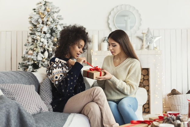 Surprise de Noël. Deux filles curieuses ouvrant un cadeau de Noël inattendu d'un admirateur secret, espace de copie