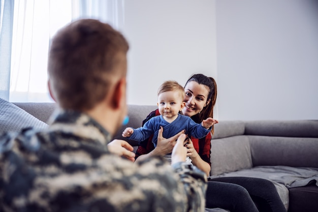 Surprise pour la famille. Le brave soldat est enfin rentré à la maison. Vue arrière du soldat tenant les bras les bras ouverts et veut embrasser son fils bien-aimé