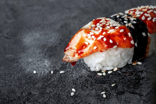 Sushi à l'anguille fumée et graines de sésame sur fond de pierre. Plat japonais Unagi sushi, gros plan