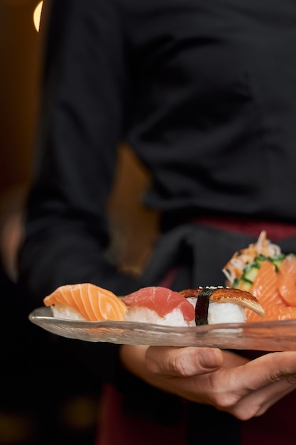 Sushi appétissant sur plaque dans les mains du personnel du restaurant
