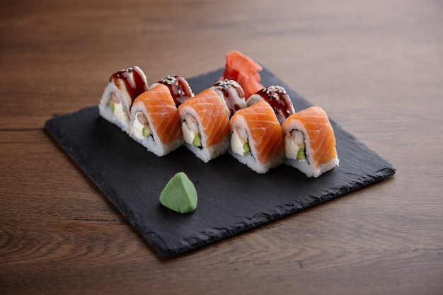 Sushi appétissant sur une plaque de pierre sur une table en bois foncé