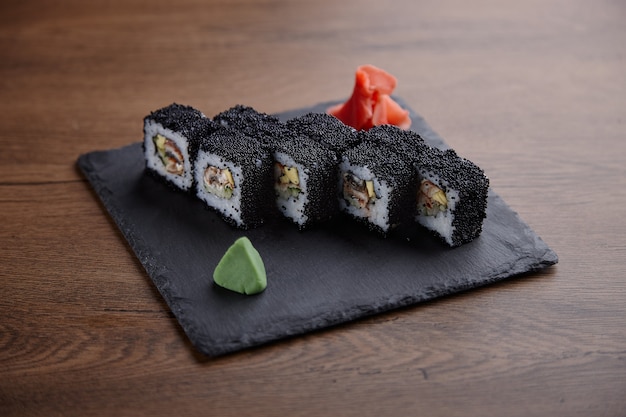 Sushi appétissant sur une plaque de pierre sur une table en bois foncé