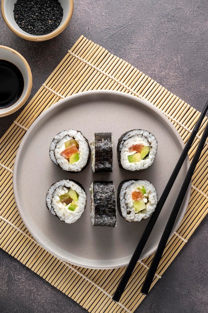 Sushi sur assiette ronde avec baguettes sauce soja gingembre Rouleaux maison au saumon avocat et concombre