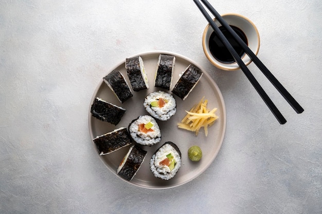 Sushi sur assiette ronde avec baguettes sauce soja gingembre Rouleaux maison au saumon avocat et concombre