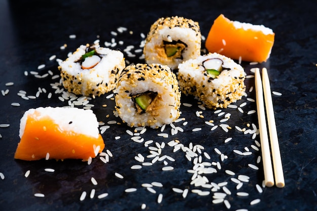 Sushi sur une assiette de table noire avec des baguettes en bois. Manger de la nourriture japonaise au restaurant.