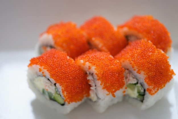 Sushi au caviar de poisson volant orange sur une plaque blanche