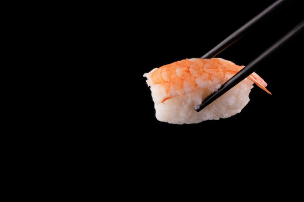 Sushi avec des baguettes sur fond noir