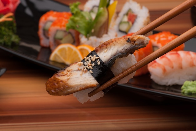 Sushi sur des baguettes se bouchent sur un fond de plats de sushi