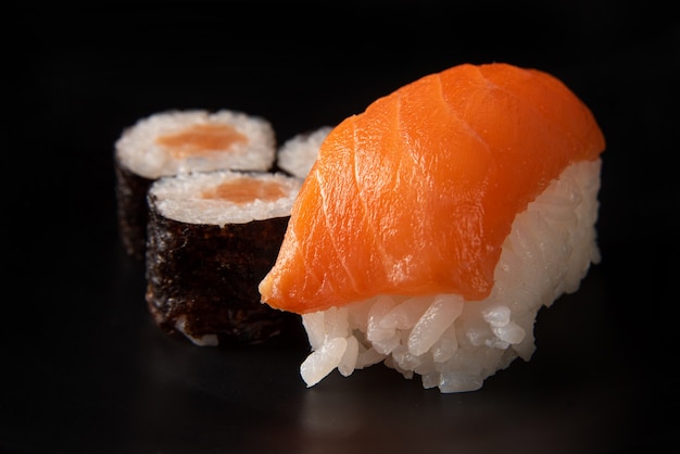 Sushi, bel arrangement de sushi fait sur une plaque noire sur une surface sombre