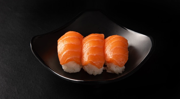 Sushi, bel arrangement de sushi fait sur une plaque noire sur une surface sombre