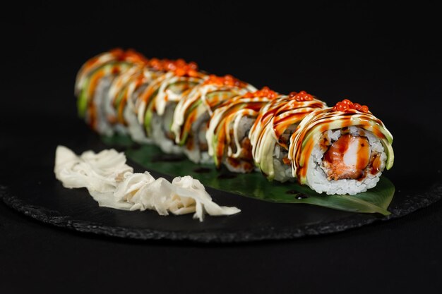 Sushi et crevettes à l'ail frites sur une plaque de pierre avec fond noir