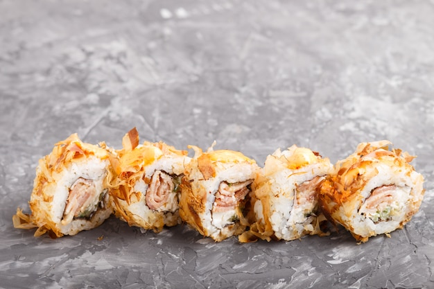 Sushi japonais maki roule avec du thon, concombre, fromage sur fond de béton noir. Vue de côté.