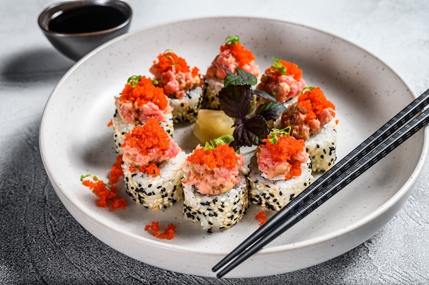 Photo sushi maki roll avec thon, saumon et caviar. fond gris. vue de dessus.