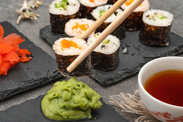 Sushi maki tenir avec des baguettes en bois et du wasabi