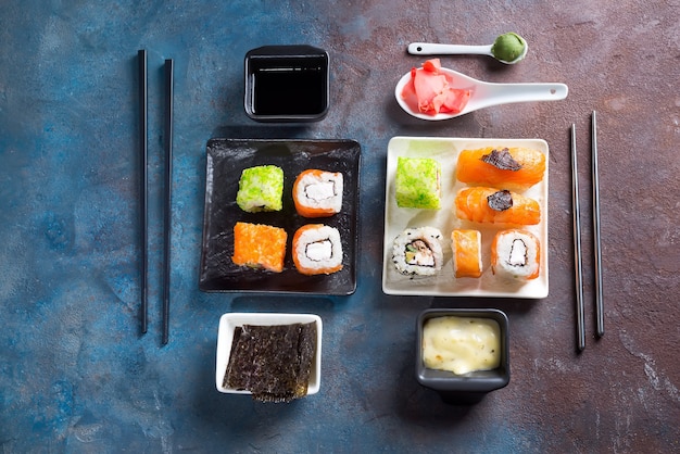 Sushi, petits pains, baguettes, sauce soja sur surface ardoise bichromie