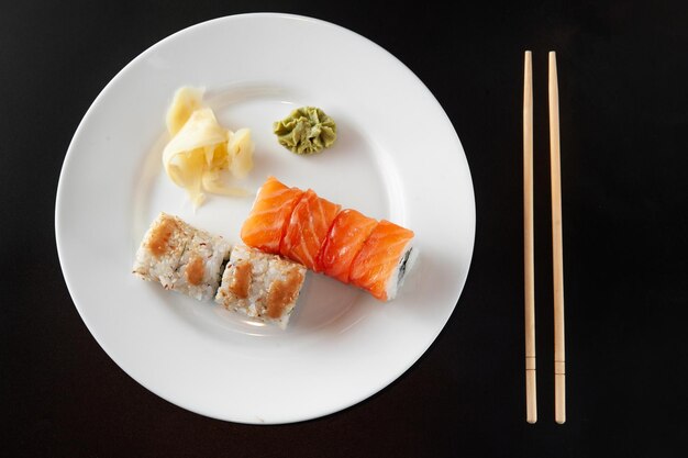 Sushi sur une plaque blanche sur fond noir