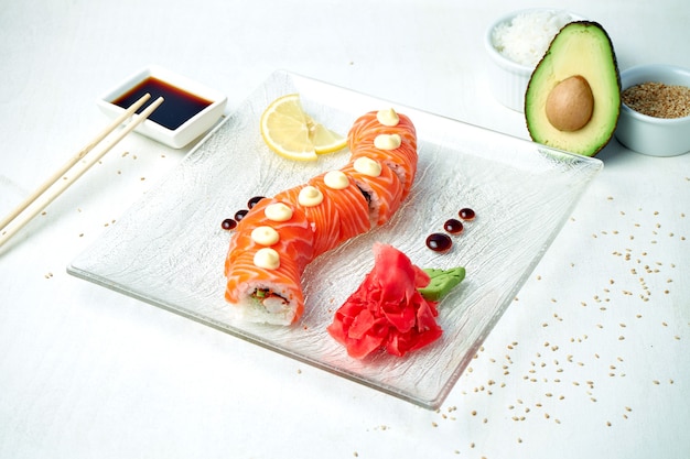 Sushi roll dragon doré au saumon et crevettes sur fond blanc