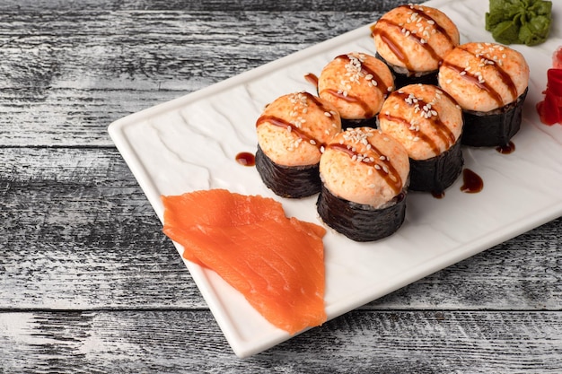 Sushi roule des sushis avec du poisson sur un fond en bois blanc