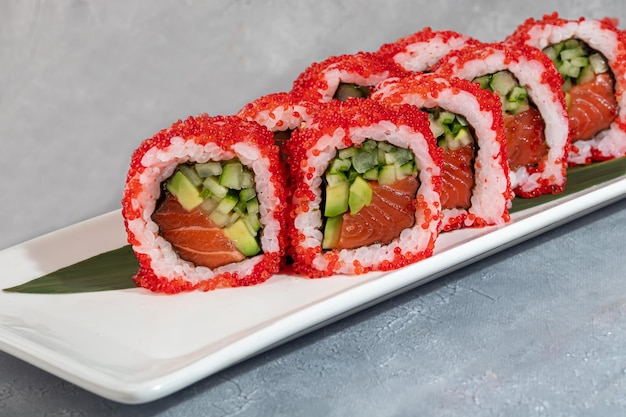 Photo sushi et rouleaux avec des crevettes de caviar et de l'avocat de thon sur un fond gris