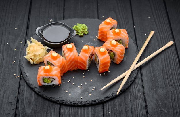 Sushi de saumon roule sur fond noir.