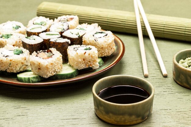 Sushi servi avec des concombres sur une assiette verte Sauce soja dans des bols