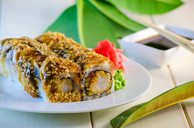 Sushi avec tempuro d'anguille et de crevette d'un plat et d'un fond blanc