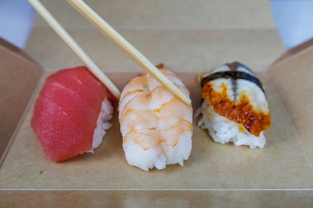 Les sushis aux crevettes de thon et à l'anguille se trouvent dans une boîte en carton sur la table de la cuisine Concept de restauration rapide