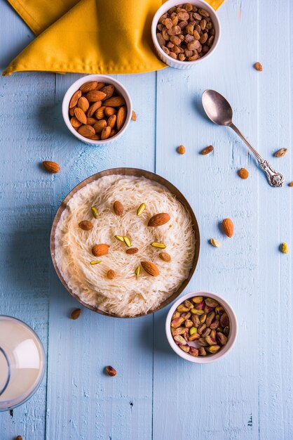 Sutarfeni sucré indien ou sutar feni ou firni ou seviyan ou laccha, râpé, farine de riz feuilleté rôti au ghee, mélangé avec du sucre fondu pour former une barbe à papa, garni de pistache et d'amandes