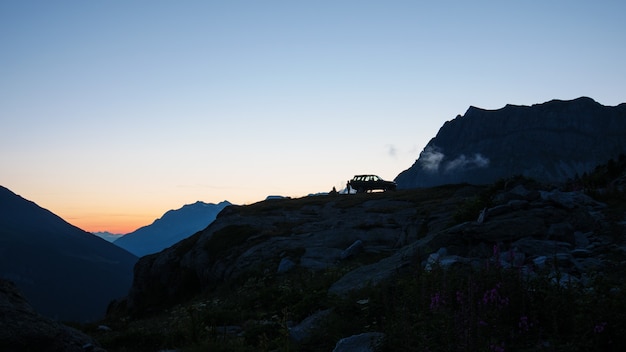 SUV 4x4 au sommet de la montagne, paysage pittoresque au coucher du soleil, exploration aventureuse sur les Alpes.