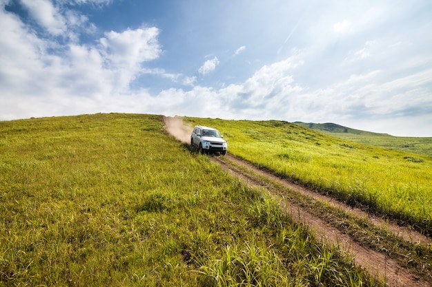 Le SUV argenté descend la colline par le chemin de terre