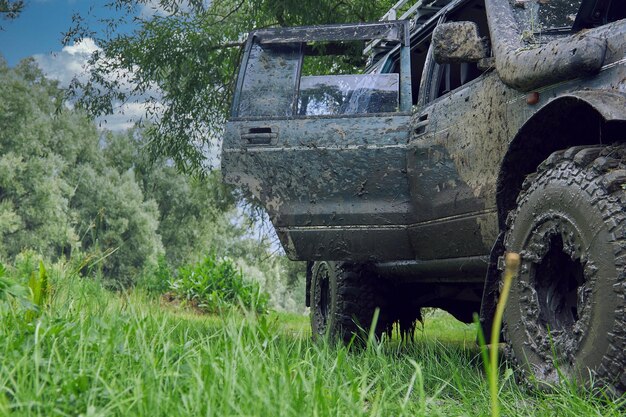 Le SUV sale après une course tout-terrain se tient dans la nature avec le capot et la porte ouverts