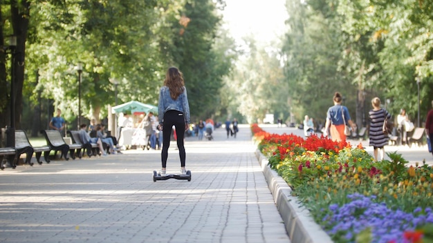 Svelte belle fille chevauchant un gyroscope dans le parc, passant de la caméra, gros plan