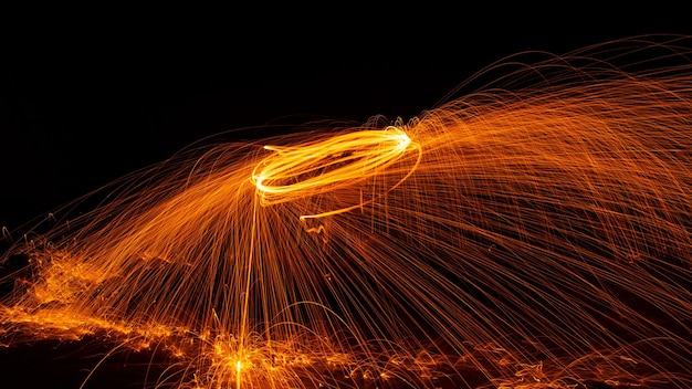 Swing fire Swirl photographie de lumière en laine d'acier avec réflexe dans l'eau longue vitesse d'exposition