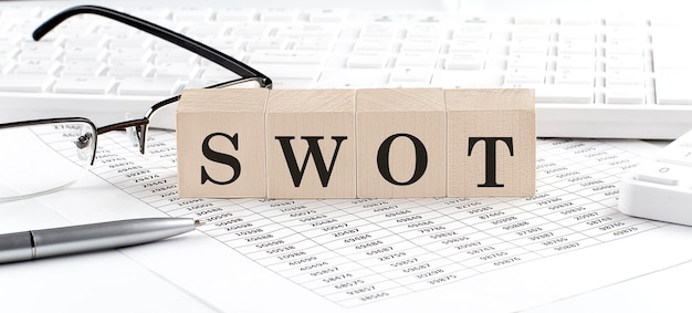 SWOT écrit sur un cube en bois avec une calculatrice à clavier chartglassesBusiness concept