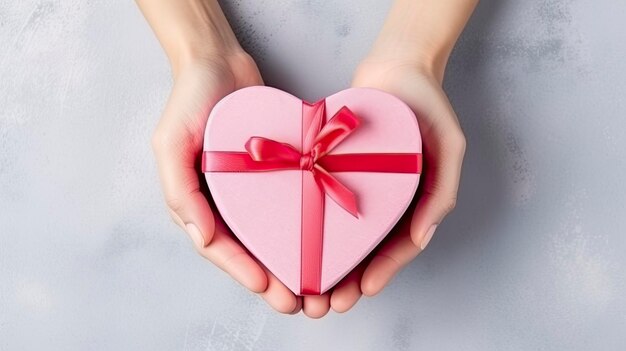 Symbole de l'amour CloseUp sur des mains féminines tenant un cadeau en forme de cœur pour la Saint-Valentin, l'anniversaire et la fête des mères