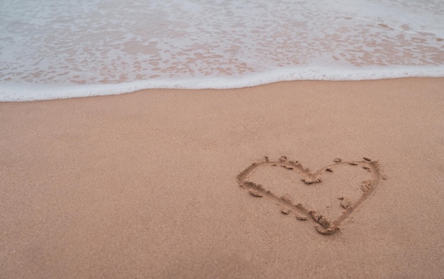 Symbole du coeur de l'amour dessiné à la main sur la plage d'été de sable