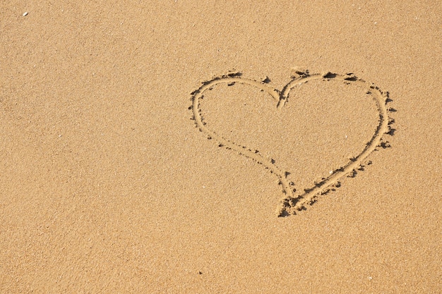 Un symbole du cœur écrit sur le sable