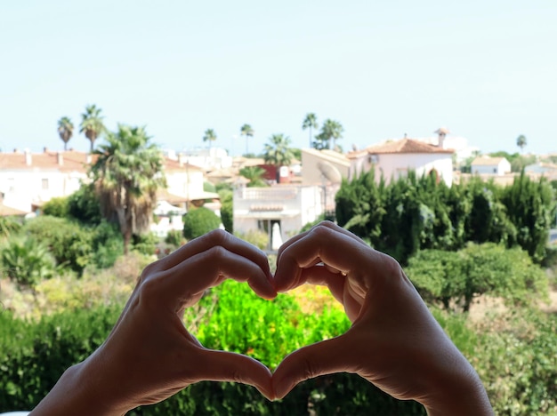 Symbole du coeur des mains sur fond de paysage espagnol, verdure, palmiers, maisons, amour