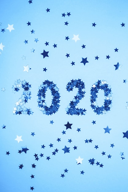 Symbole du nouvel an 2020 de confettis or sur fond bleu.