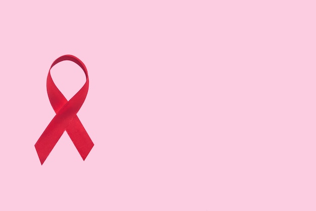 Symbole du ruban rouge de la journée mondiale du sida sur fond rose avec espace de copie