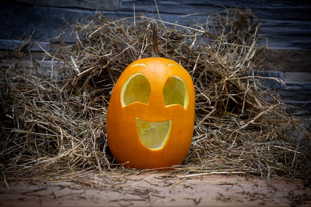 Le symbole d'Halloween de citrouille souriante jaune et heureuse se dresse sur un foin et un standJack o lantern en bois