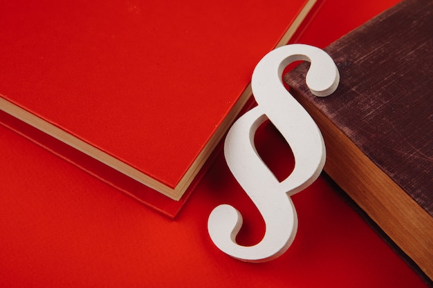 Symbole de paragraphe en bois avec des livres sur fond rouge.