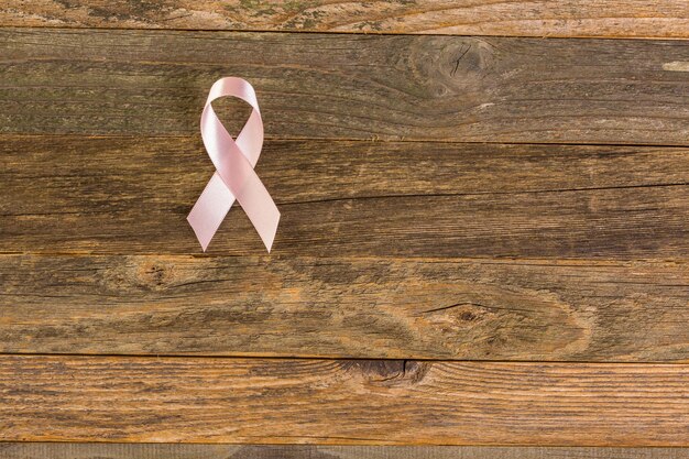 Symbole de santé des femmes en ruban rose sur planche de bois.