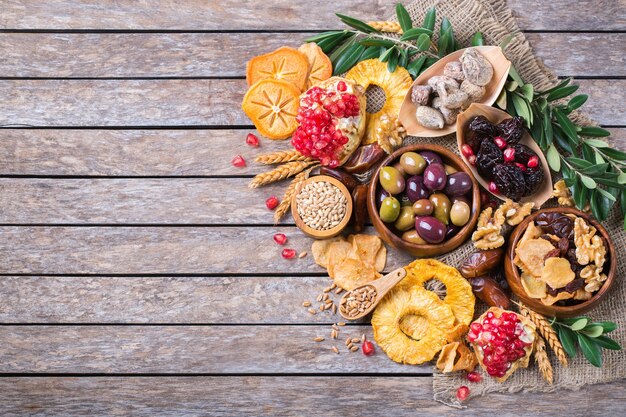 Symboles de la fête judaïque Tu Bishvat, Rosh Hashana nouvel an des arbres. Mélange de fruits secs, date, figue, raisin, orge, blé, olive, grenade sur une table en bois. Copiez l'arrière-plan plat de l'espace