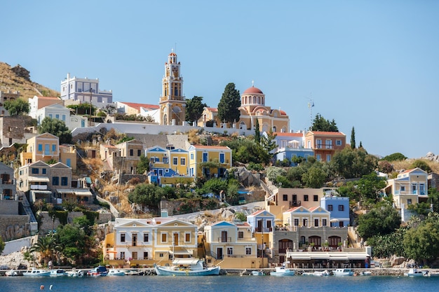 SYMI, GRÈCE - 12 JUIN 2015 : Vue d'une rue côtière et de bateaux de pêche amarrés dans le port de Yialos le 12 juin 2015 sur l'île de Symi, Grèce. Symi est la destination facile et la plus populaire pour les excursions d'une journée f