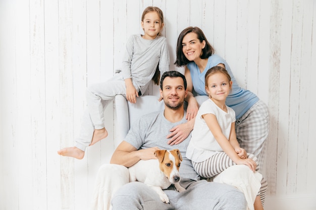 Sympathique famille de quatre membres: femme brune, son mari, ses deux filles et son animal de compagnie préféré