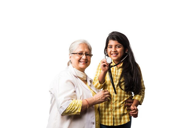 Sympathique femme médecin pédiatrique asiatique indienne senior avec jolie petite fille patiente, isolée sur blanc